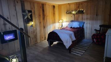 Een knus slaapkamer met een houten wand, een bed met een rood-wit geruit plaid, een nachtkastje met een lamp en een kleine decoratieve ster aan de wand.