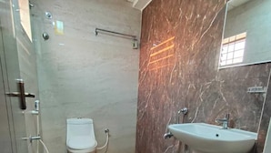 A bathroom with a toilet, sink, and marble walls. - MK GRANDE (Bengaluru)