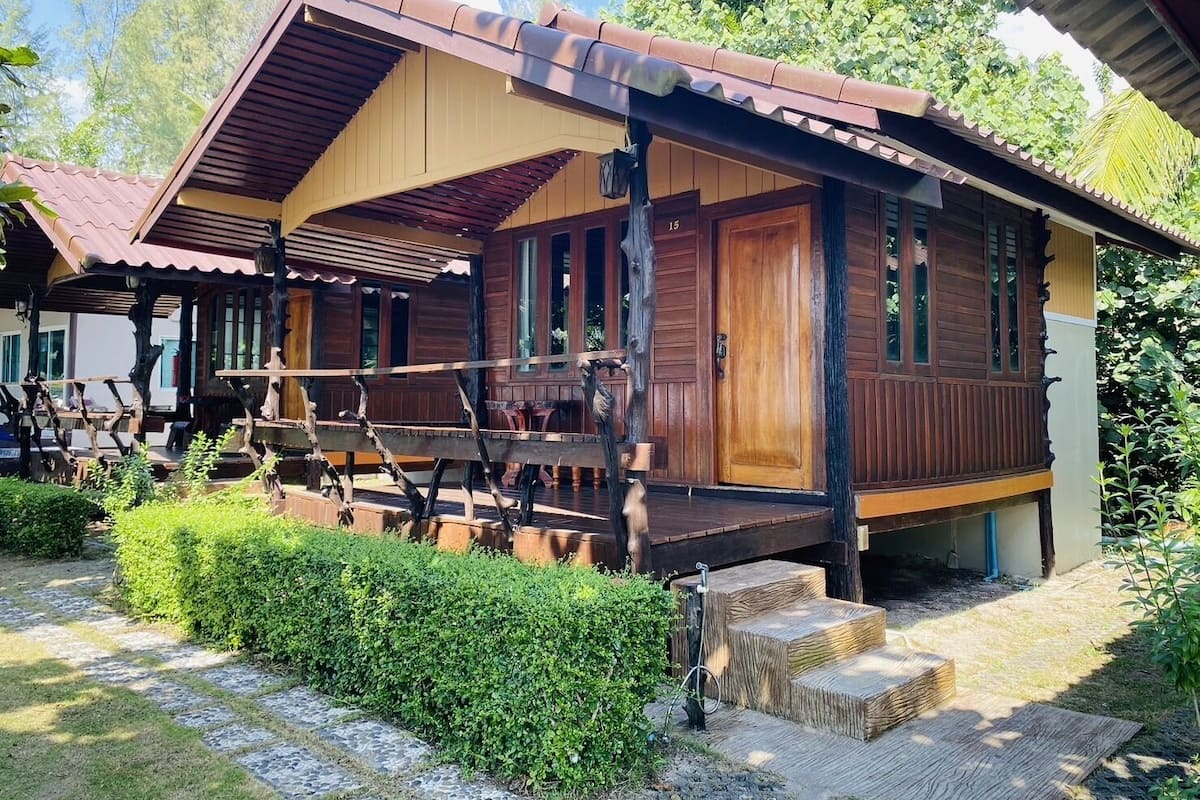 A wooden cabin with a porch, a door marked '15', and a small staircase leading to the entrance.