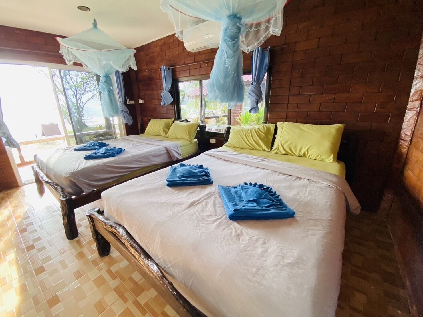 A hotel room with two beds, each with a canopy and blue towels.