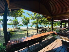 A wooden deck with benches overlooking a beach.