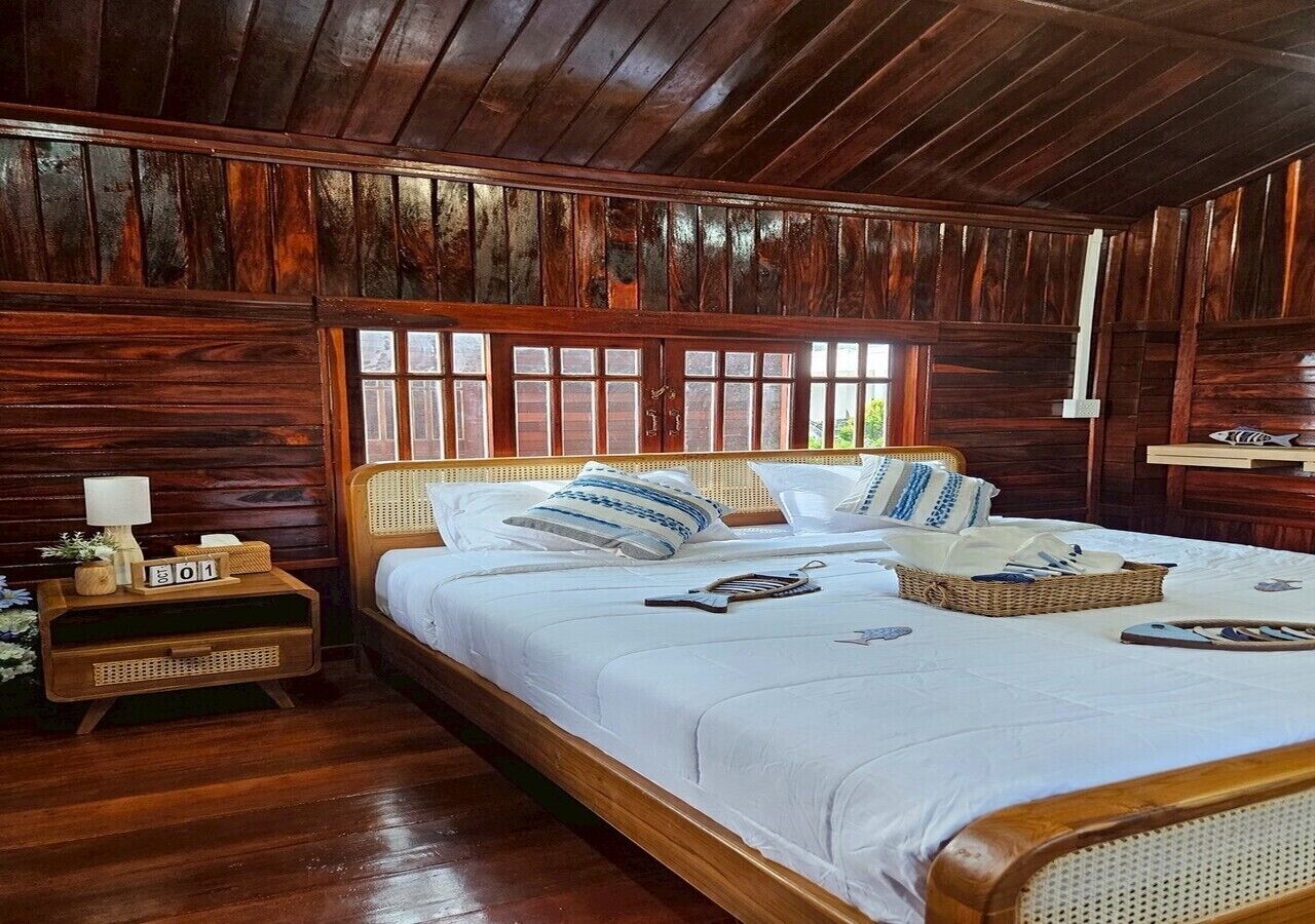 A wooden-paneled room with a large bed, a nightstand, and a window.