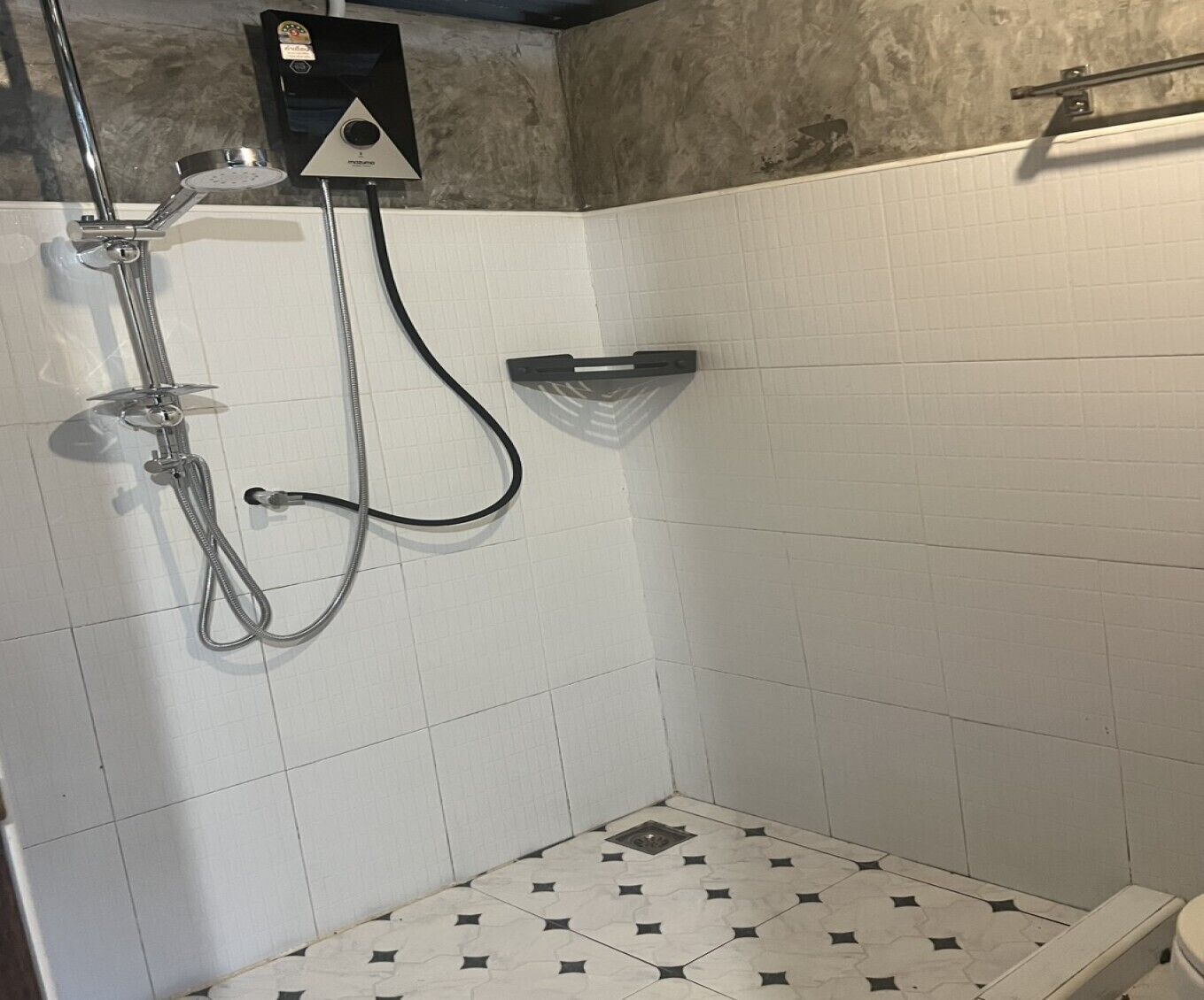 A shower with a handheld showerhead, a wall-mounted faucet, and a control panel.