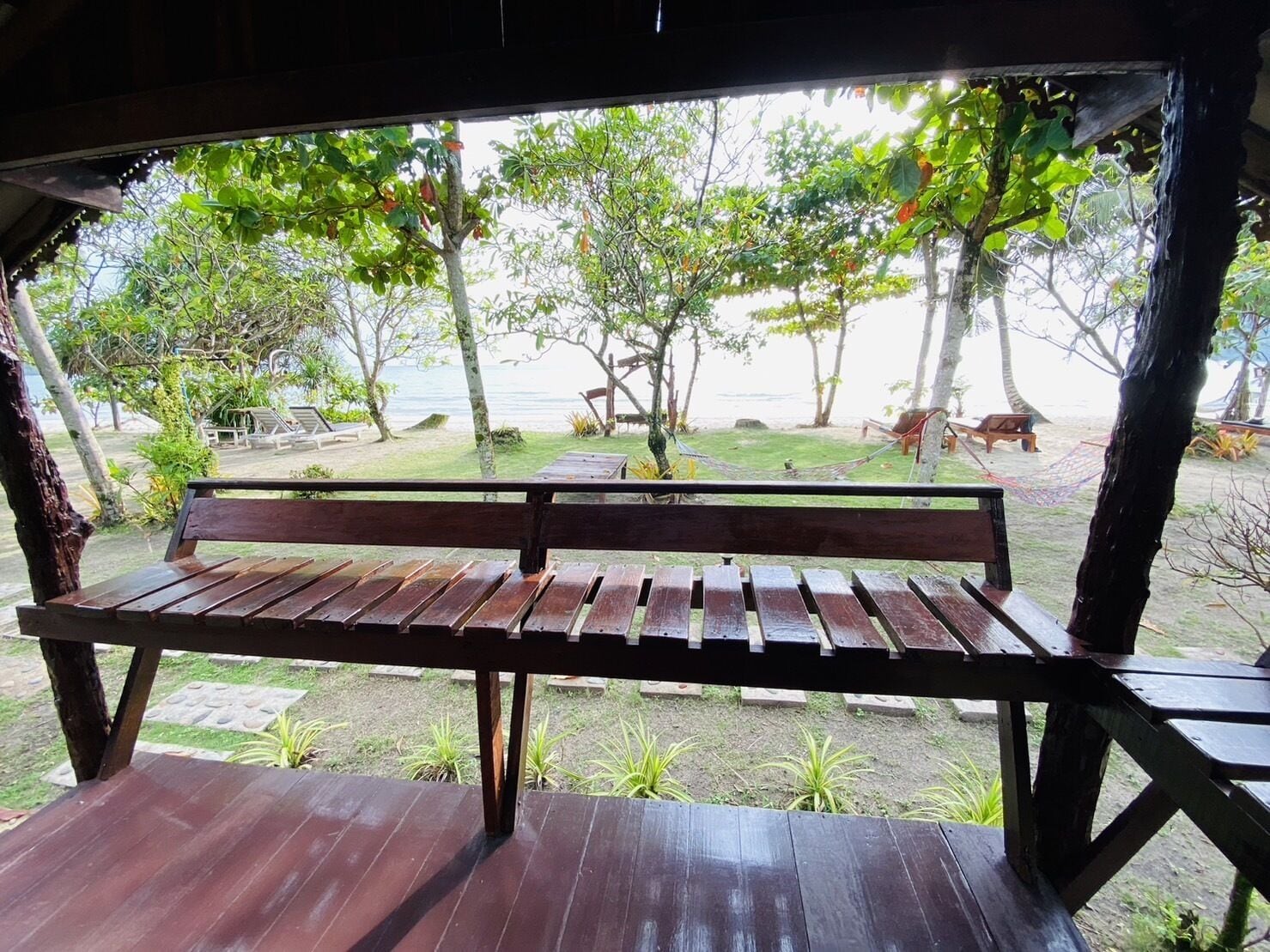Un banco de madera con vistas a una playa y árboles.