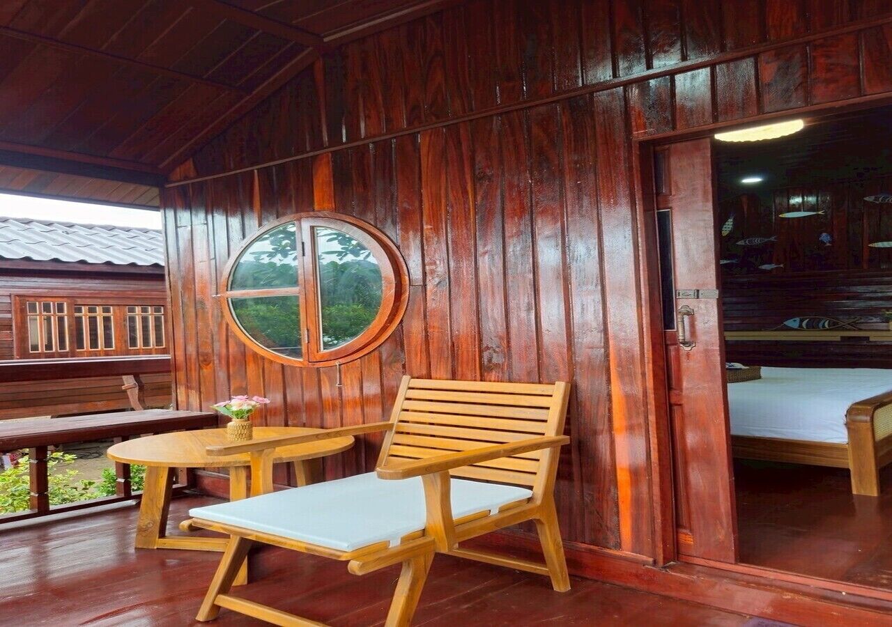 A wooden cabin with a round window, two wooden chairs, and a table.