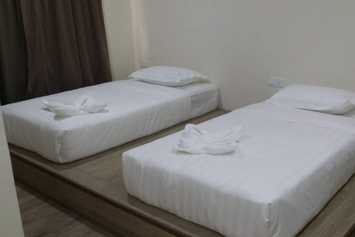 A hotel room with two single beds, each with white linens and a towel on the bed.
