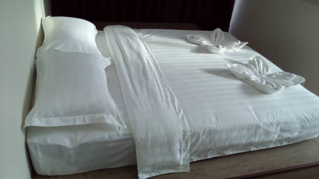 A neatly made bed with white linens and a decorative pillow arrangement.