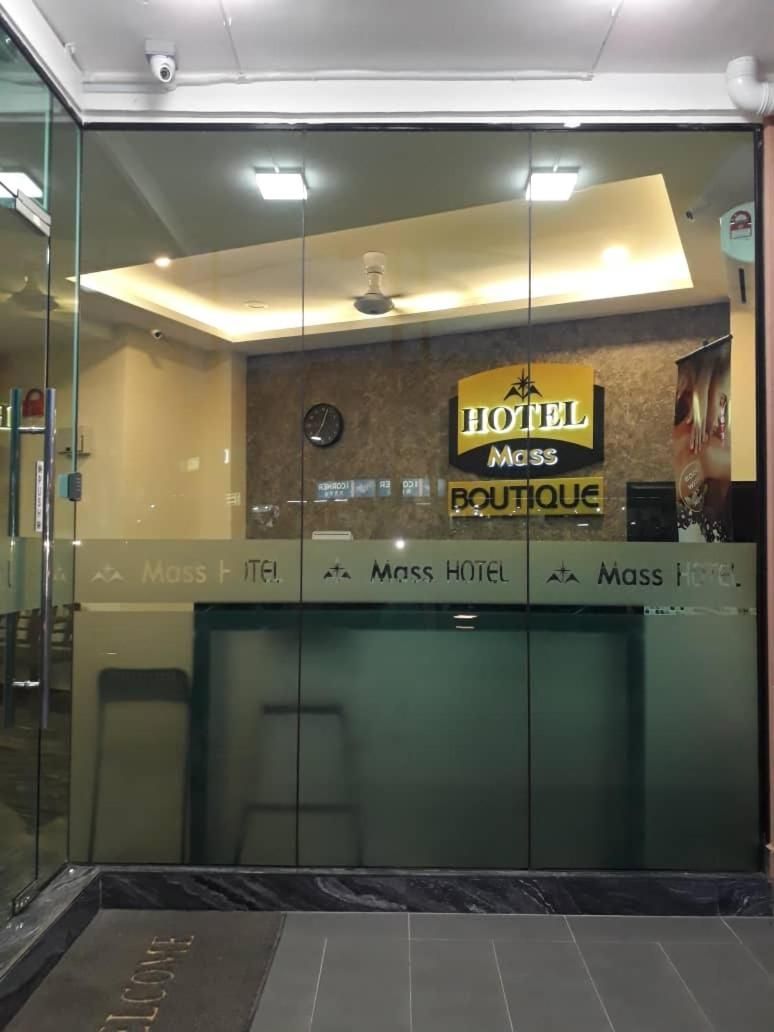 Un área de recepción con un muro de vidrio, un reloj y un letrero que dice 'Mass Hotel Boutique'.