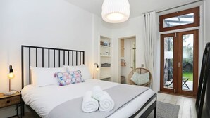 Een keurig opgemaakt slaapkamer met een bed, bedlampjes, een kledingkast en uitzicht door een glazen deur.