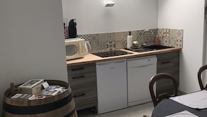 Eine kleine Küche mit Oberlicht, einer Mikrowelle, einem Wasserkocher, einer Spüle und einem kleinen Kühlschrank.