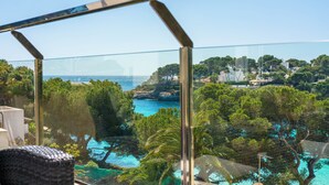 Een glazen balkon met uitzicht op een kustlandschap, inclusief een waterpartij en begroeiing.