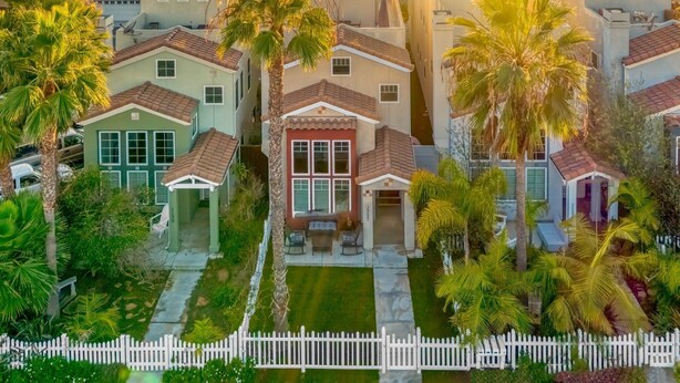 A residential area with houses featuring red-tiled roofs, surrounded by palm trees and a white picket fence. - ☀️HUGE Beach House!☀️3 blocks to BEACH🏖Ocean View🏝 3 BR/2.5BA (Oceanside)