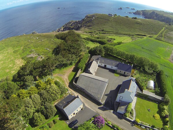 An aerial view of a rural property with a large barn, a farmhouse, and a field.