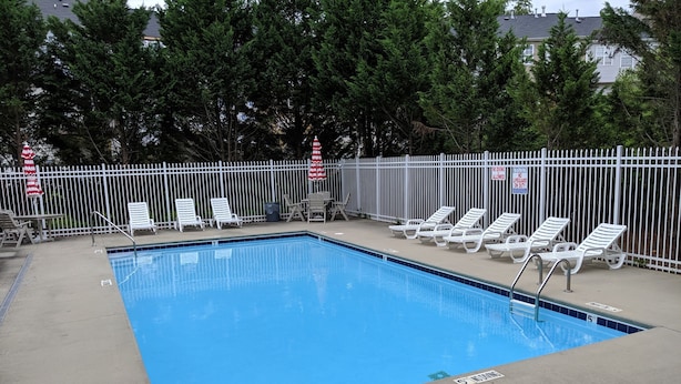 A rectangular pool with a white fence and lounge chairs. - Cozy and Convenient Furnished Townhome w/view (High Point)