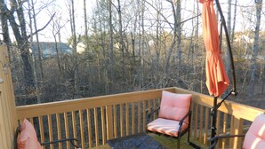A wooden deck with a table and two chairs, an umbrella, and a view of trees. - Cozy and Convenient Furnished Townhome w/view (High Point)
