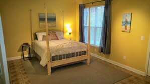 A bedroom with a four-poster bed, a nightstand, a lamp, a window with curtains, and a painting on the wall. - Cozy and Convenient Furnished Townhome w/view (High Point)