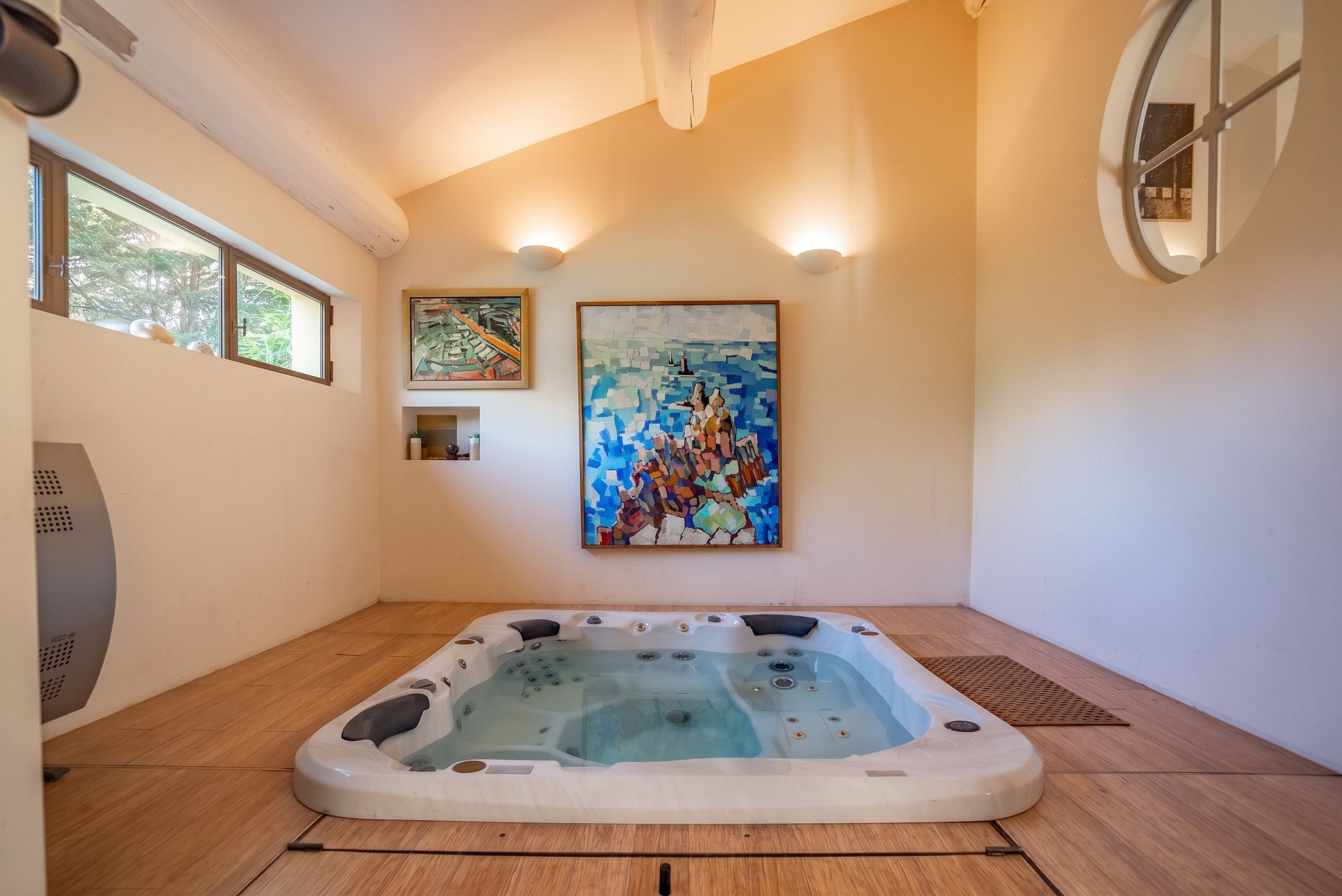 Une salle de spa équipée d’un bain à remous, d’un plancher en bois et ornée de deux tableaux.