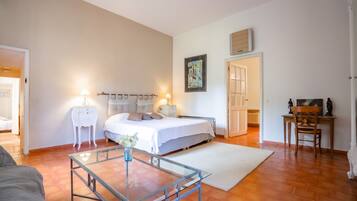 Ein Schlafzimmer mit einem Bett, Nachttischen, einem Glastisch, einer Heizung und einem Bild an der Wand.