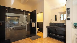 Une salle de bain moderne avec une douche à parois de verre, un meuble-lavabo noir et un plancher en bois.