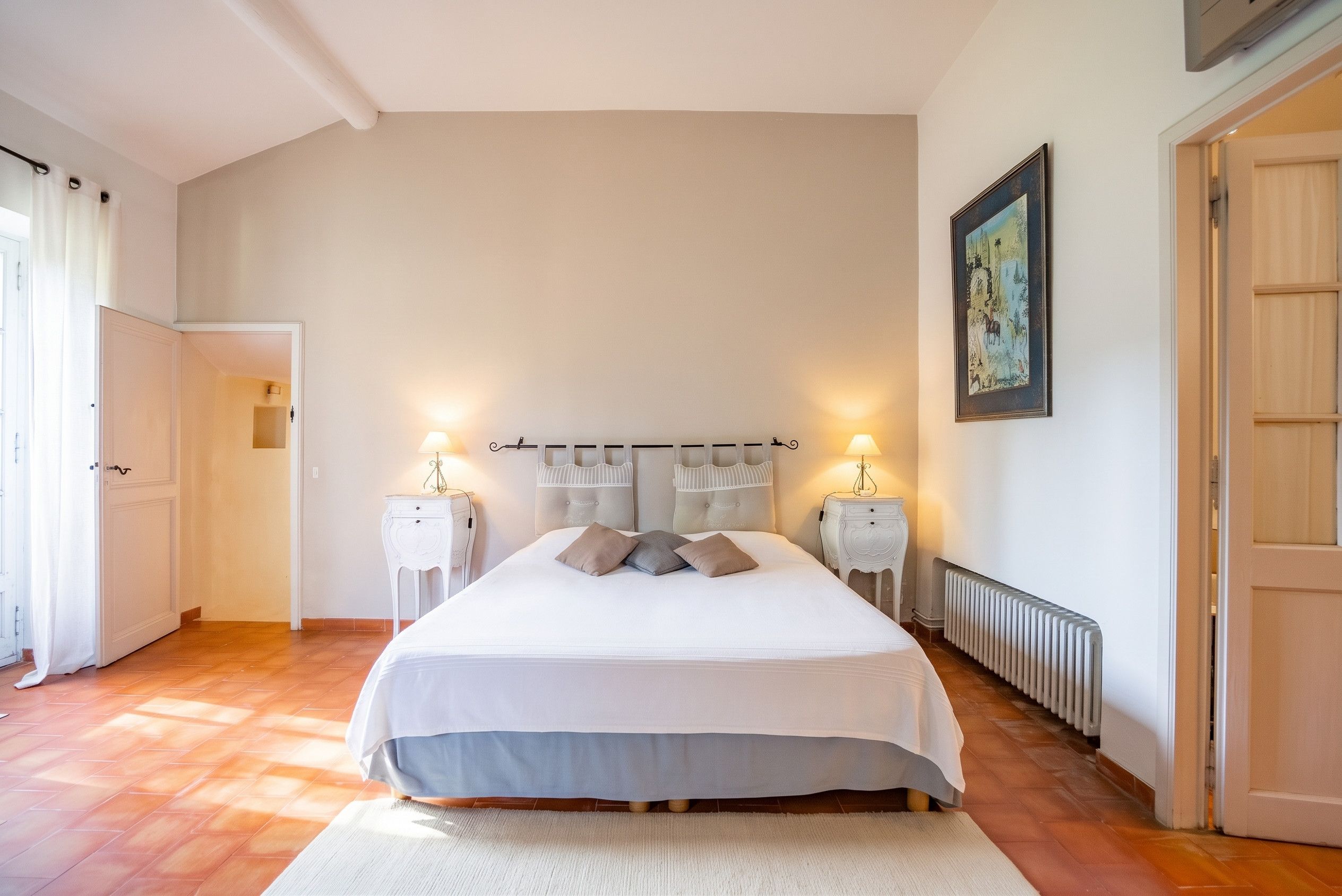 Une chambre à coucher avec un grand lit, deux tables de chevet, un radiateur et une porte.