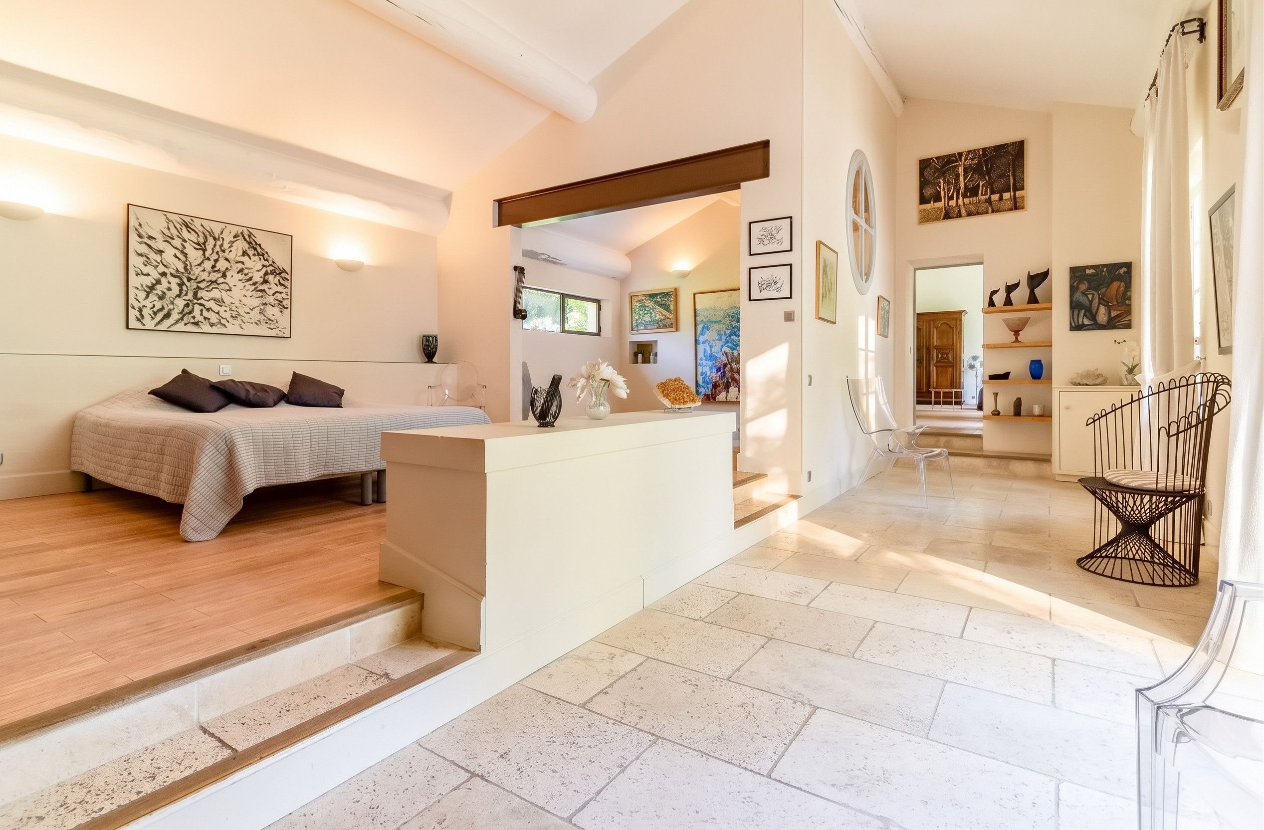 Ein modernes Interieur mit einem Bett, einer kleinen Sitzecke und Kunstwerken an den Wänden.