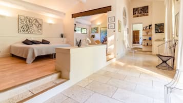 Ein modernes Interieur mit einem Bett, einer kleinen Sitzecke und Kunstwerken an den Wänden.