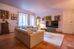 Een woonkamer met een bank, een televisie en een open haard.