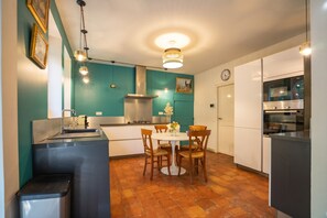 A modern kitchen with teal walls, a dining table with chairs, and a built-in oven.