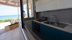 Una cocina con vistas al mar, una estufa a gas, un lavamanos y armarios azules.