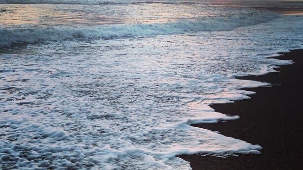 Una playa con olas y un atardecer.