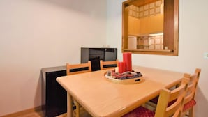 Un coin repas avec une table et des chaises en bois, un petit réfrigérateur noir et un miroir au mur.