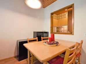 A dining area with a wooden table and chairs, a small black refrigerator, and a mirror on the wall.