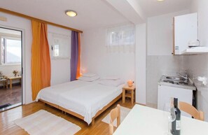 A bedroom with a bed, bedside table, and a small table with a lamp.