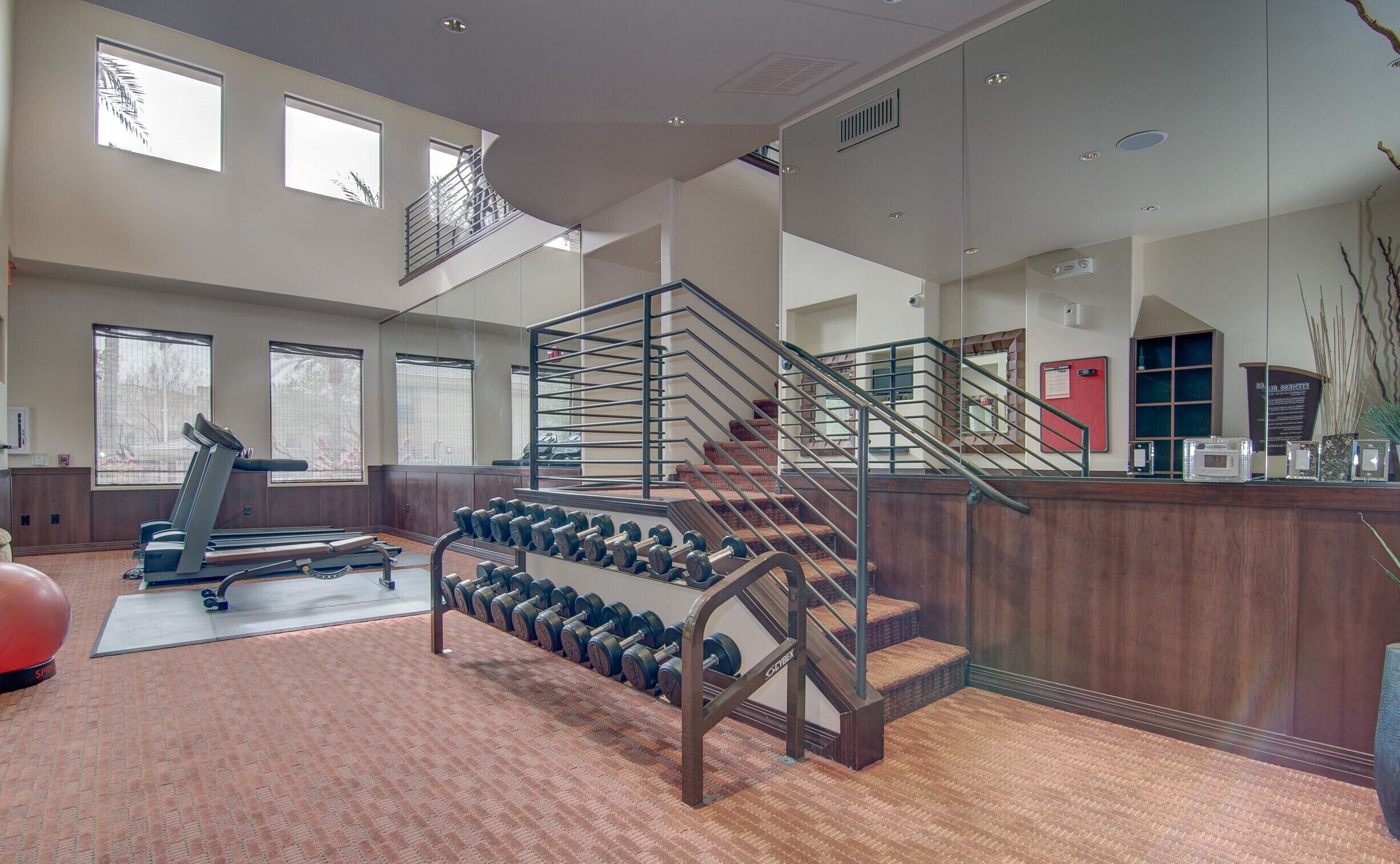 Une salle de sport spacieuse équipée d’un tapis de course, d’haltères et d’un escalier.