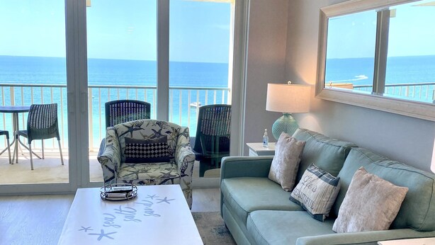 A spacious living area with a view of the ocean, a ceiling fan, a white coffee table, a green sofa, and a patterned armchair. - Apollo 9th floor private beachfront balcony  **Majestic Views* (Marco Island)