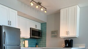 A modern kitchen with white cabinets, a stainless steel refrigerator, a microwave, and a coffee maker. - Apollo 9th floor private beachfront balcony  **Majestic Views* (Marco Island)