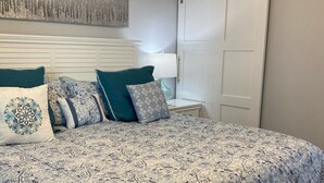 A bedroom with a large bed, a nightstand, a lamp, a wardrobe, and a decorative wall piece. - Apollo 9th floor private beachfront balcony  **Majestic Views* (Marco Island)