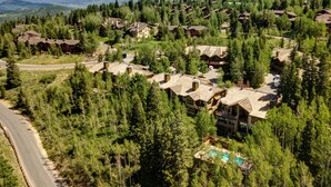 A resort with multiple cabins surrounded by dense forest, a winding road, and a visible swimming pool. - 4 Bdr/4.5Bath-Steps to lifts and Stein Eriksen (Park City)