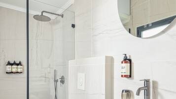 Un baño moderno con ducha de vidrio, lavamanos blanco y inodoro.
