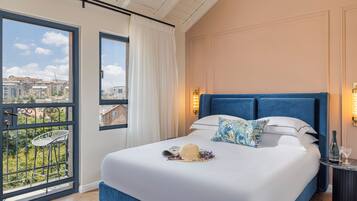 Un dormitorio con una cama grande, vistas de edificios a través de una ventana y un balcón con una silla.