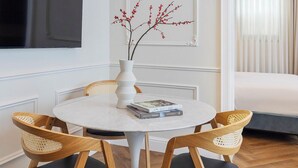 A dining area with a round table, four wooden chairs, a white vase with red branches, and a modern pendant light. -  Villa Albi - Machne Yehuda Hotel (Jerusalem)