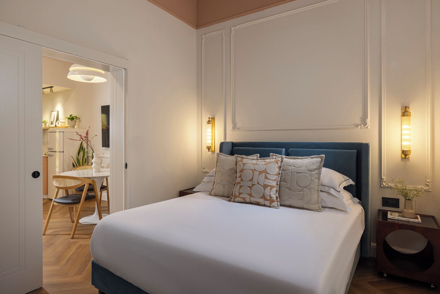 Un dormitorio ordenado con una cama grande, mesitas de noche y vista hacia la habitación contigua.