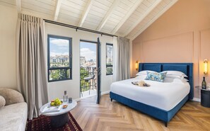 Un dormitorio amplio con una cama grande, un balcón con vistas a la ciudad y un comedor con mesa y sillas.