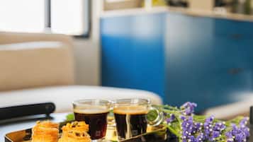 A tray with pastries and drinks on a table, with a window and a patterned wall in the background.