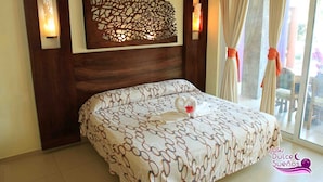 A bedroom with a bed, a decorative wall panel, and a window with curtains. - VILLAS DULCE SUEÑOS (Rincón de Guayabitos)