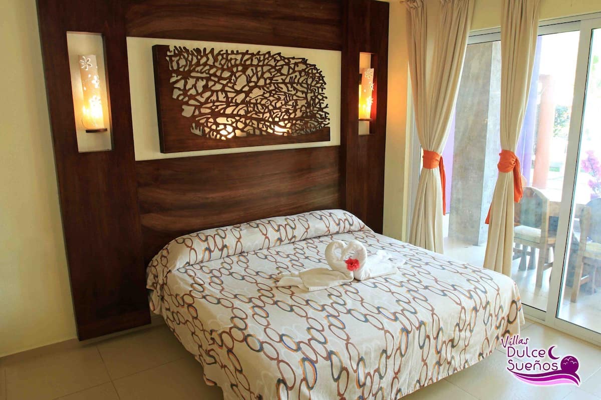 A bedroom with a bed, a decorative wall panel, and a window with curtains.