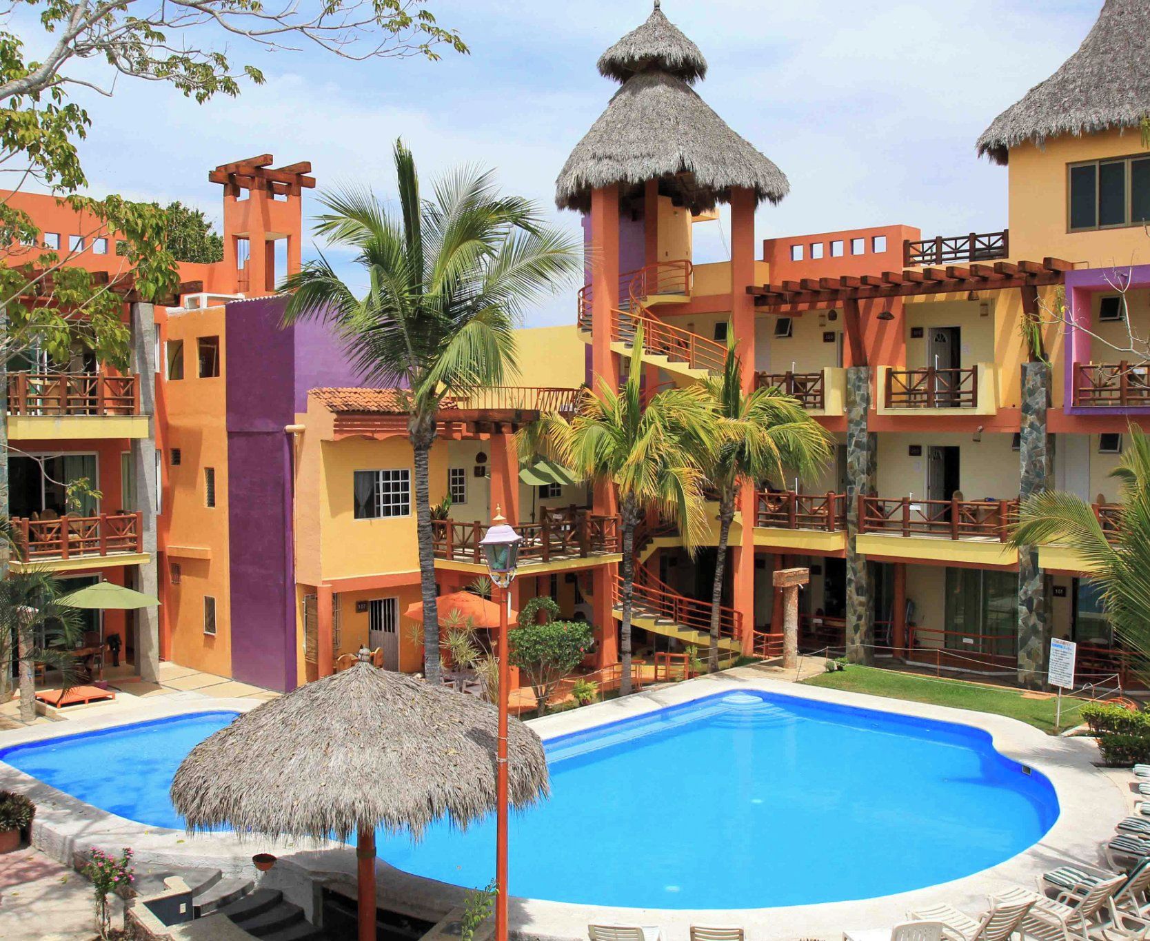 Un resort con piscina, varios balcones y construcciones de techo de paja.