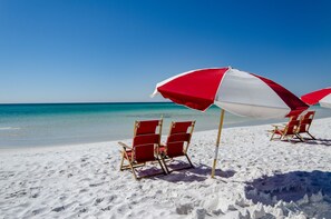 Une plage avec des chaises longues et des parasols rouges et blancs.