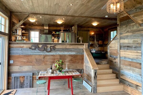 A rustic wooden interior with a dining area, staircase, and kitchen.