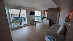 Een moderne woonkamer met een bank, een eettafel en een balkon met uitzicht op zee.